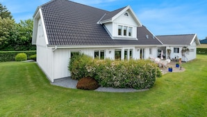 Een tweelaags huis met een donker betegeld dak, witte buitenmuren en een verzorgd gazon.