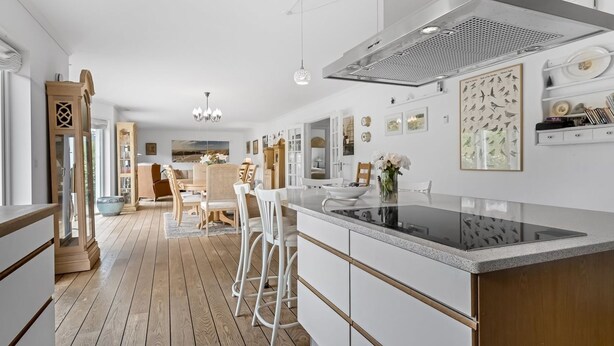 Een moderne keuken met witte kasten, een groot eiland en een houten vloer.