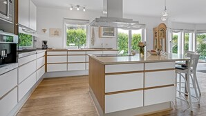 Een moderne keuken met witte kasten, een centraal eiland en uitzicht op groen.