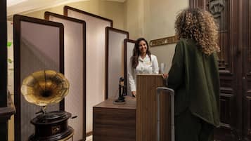 A reception area with a wooden desk, a vintage gramophone, and a suitcase.