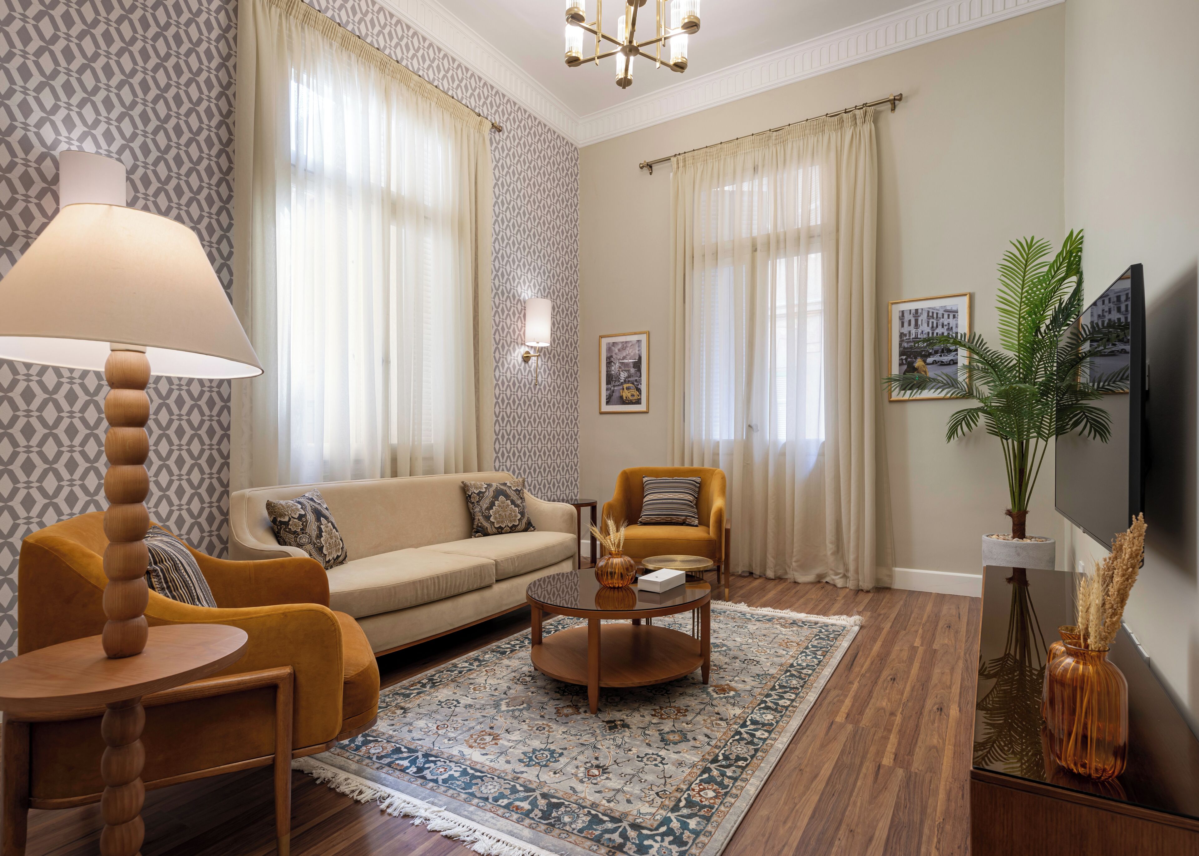Una sala de estar con sofá, sillones, una mesa de centro, una lámpara, televisor y una planta.