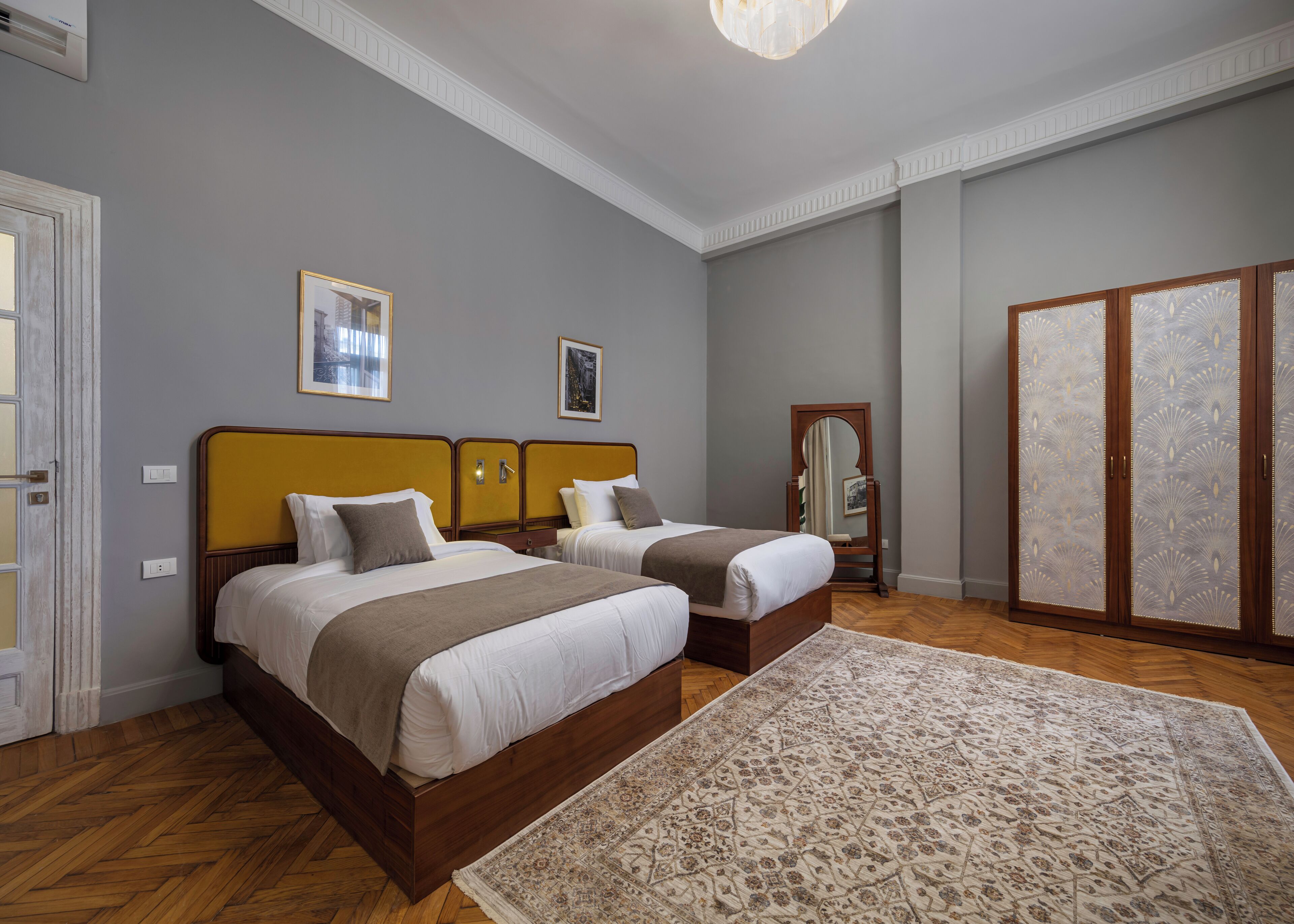 Une chambre avec deux lits, un grand miroir et une armoire.