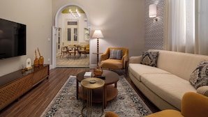 A living room with a sofa, armchair, coffee table, TV, and a patterned rug. - Boutique Residence Layal-Lemon Spaces (Cairo)