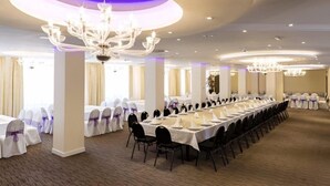 A banquet hall with long tables, white tablecloths, and purple sashes. - Donix Suites  (Njoro)