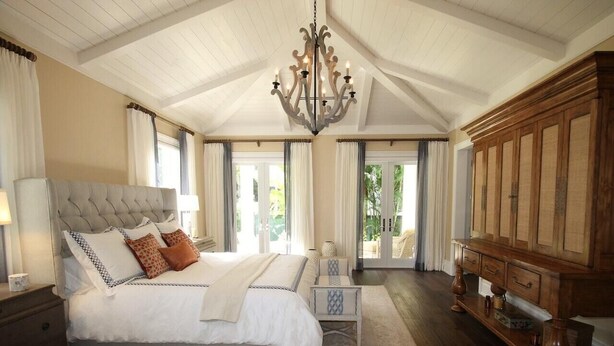 A spacious bedroom with a large bed, a wooden cabinet, and a chandelier. - Donix Suites  (Njoro)