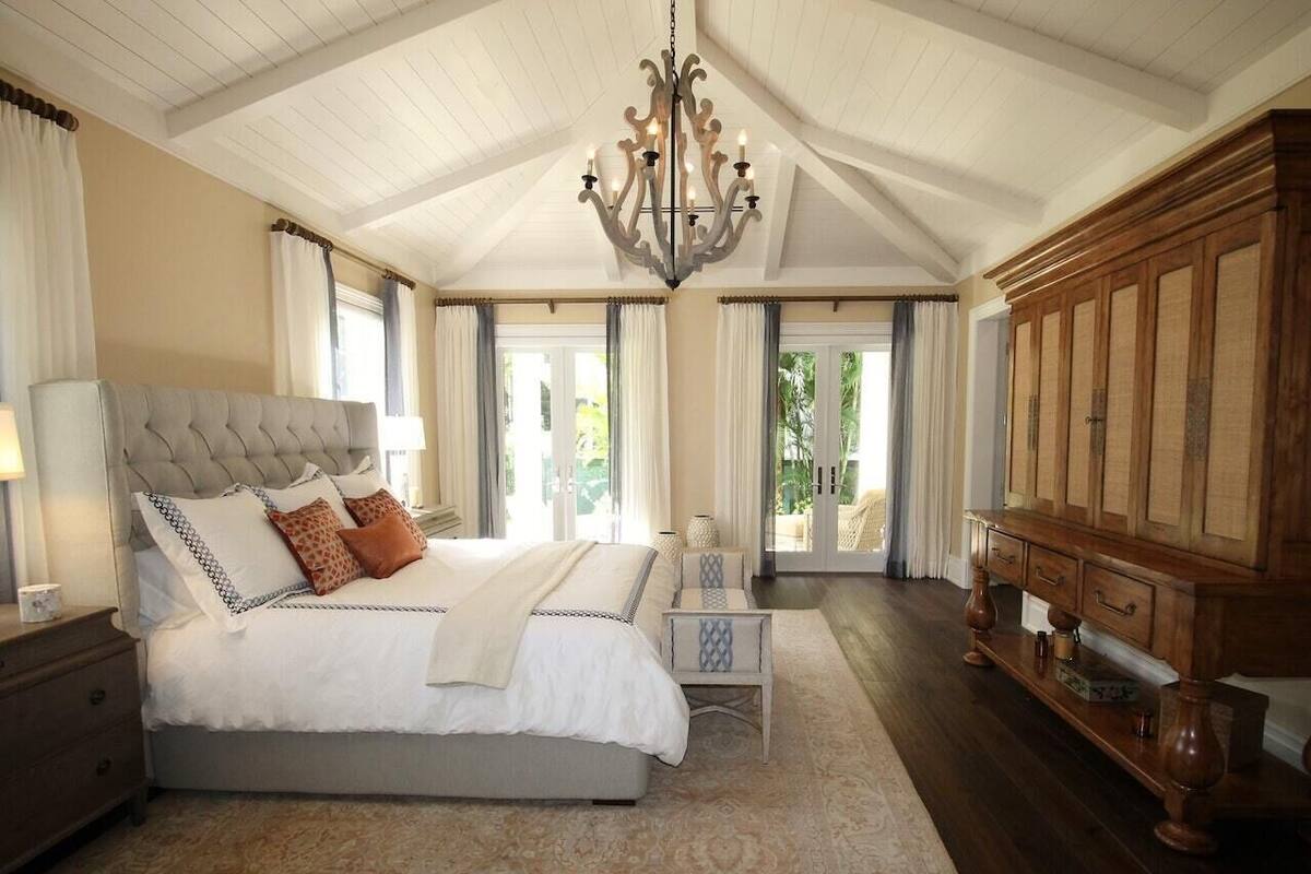 A spacious bedroom with a large bed, a wooden cabinet, and a chandelier.