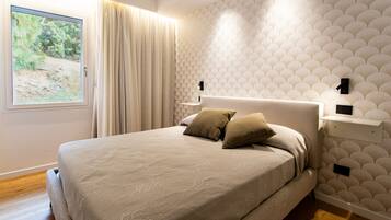 Une chambre avec un grand lit, une fenêtre avec des rideaux, un mur à motifs et une table de chevet avec une lampe.