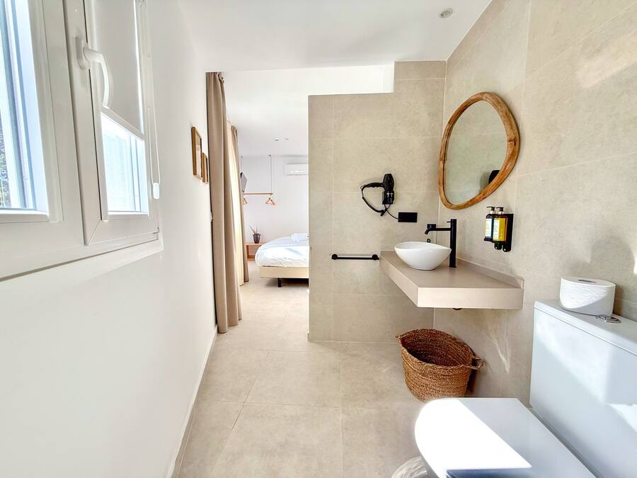 Um banheiro moderno com pia branca, espelho e vaso sanitário.
