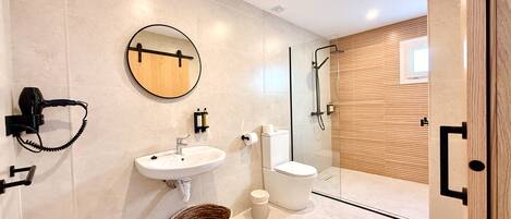 Un baño moderno con lavamanos, inodoro y ducha.
