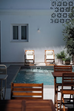 Una piscina al aire libre, sillones reclinables de piscina