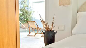 Un dormitorio con cama, planta en maceta, silla y vista al exterior.