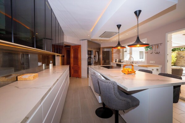 A modern kitchen with a central island, pendant lighting, and a view to the outdoor area.