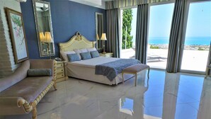 Une chambre spacieuse avec un grand lit, une chaise longue et une vue sur la mer.