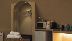 A bedroom with a bed, a small kitchenette, a microwave, a coffee maker, and a hanging clothes rack. - Nausicaa Guesthouse Marsala, Igloo in an oasis among the sea, olive trees and vineyards (Marsala)