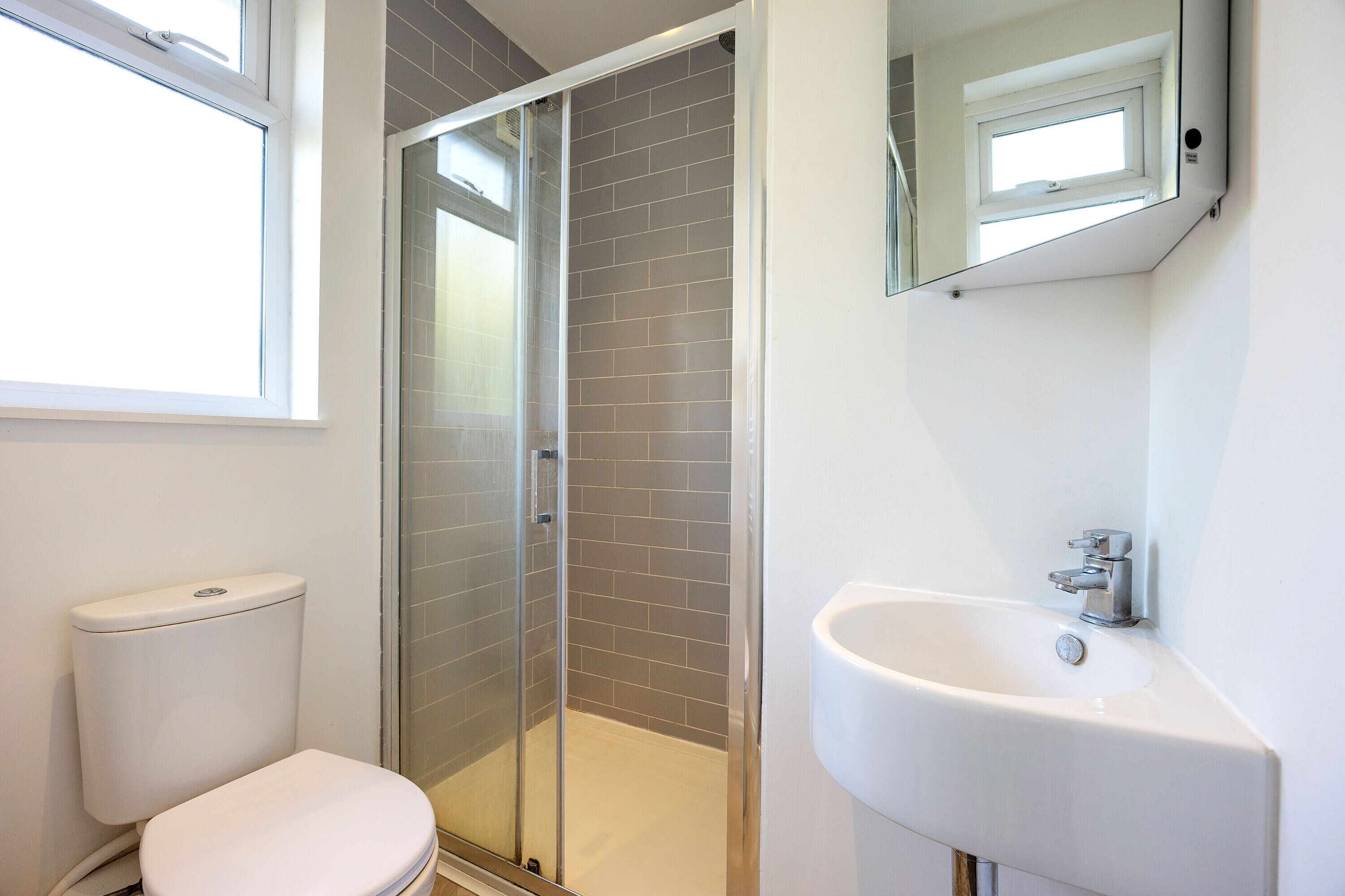 Une salle de bain comprenant des toilettes, une douche à parois de verre et un lavabo.