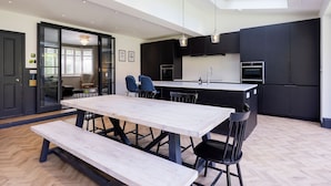 Una cocina moderna con una isla central, armarios negros y un comedor con mesa de madera y bancos.