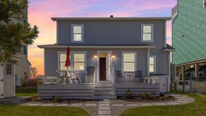 Une maison à deux étages avec un porche à l’avant, un petit jardin et un chemin menant à l’entrée.