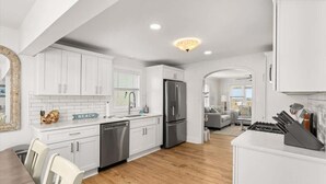 Une cuisine moderne avec des meubles blancs, des appareils en acier inoxydable et un plancher en bois.