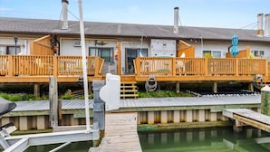 A row of cabins with wooden decks and a dock extending into a calm body of water. - Blue Horizon at Old Port (Ocean City)