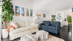 A living room with striped sofas, a coffee table, and a potted plant. - Blue Horizon at Old Port (Ocean City)