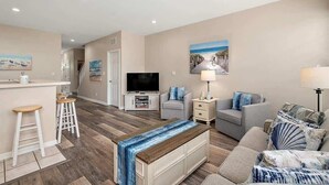 A modern living room with a TV, bar area, and seating.
