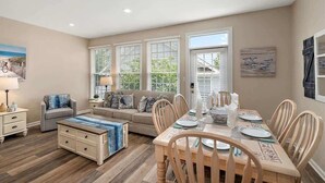 A spacious living room with a dining area, large windows, and a view of the outdoors.