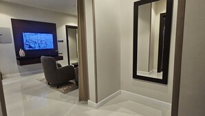 A modern living room with a flat-screen TV, a large mirror, and a comfortable seating area. - Hams Apartments (Duba)