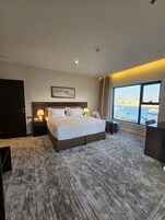 Una habitación de hotel moderna con una cama grande, un escritorio, una silla y vistas al mar.