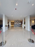 Un vestíbulo de hotel con mostrador de recepción, zona de estar y mostrador de información.