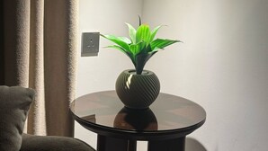 A corner of a room with a round table, a potted plant, and a wall socket. - Hams Apartments (Duba)