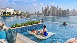 A pool area with loungers and a view of a city skyline. - Seven Palm - 1421 Studio (Dubai)