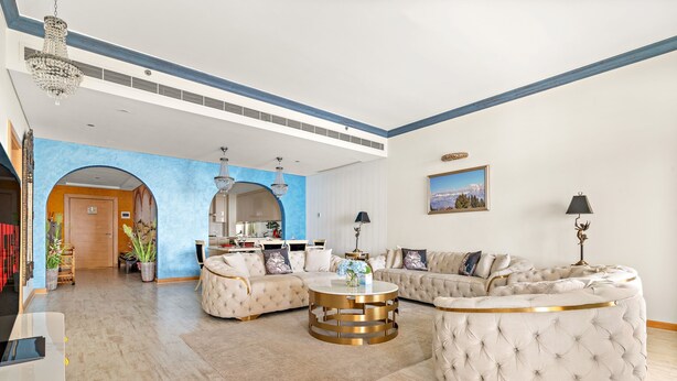 A spacious living room with a large sofa, a round gold-framed coffee table, and a chandelier. - Al Dabas - 707 2BD (Dubai)