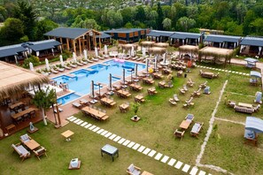 Un resort con piscina central, zonas de estar al aire libre y construcciones de techo de paja.