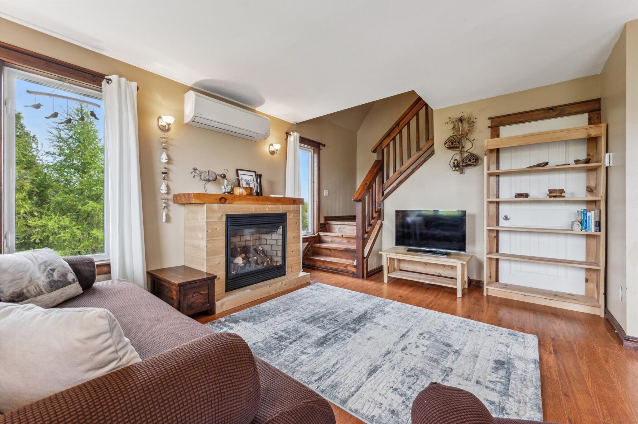 Un salón acogedor con chimenea, escalera de madera y televisor.