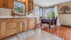 A kitchen with wooden cabinets, a dining table with chairs, and a large window.