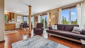 A spacious living room with a sofa, armchair, and dining area.