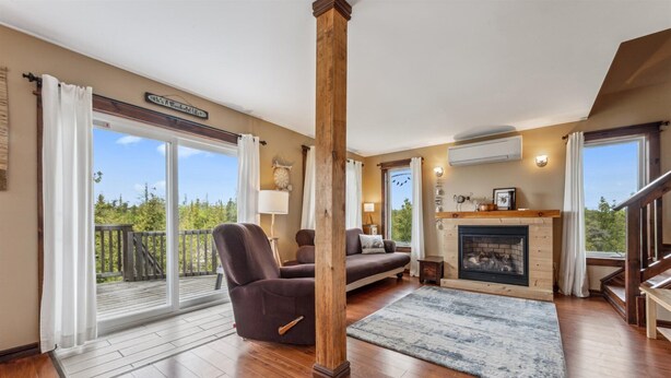 A spacious living room with a large window, a fireplace, and a wooden column.