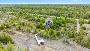 A house surrounded by dense forest with a dirt path leading to a dock.