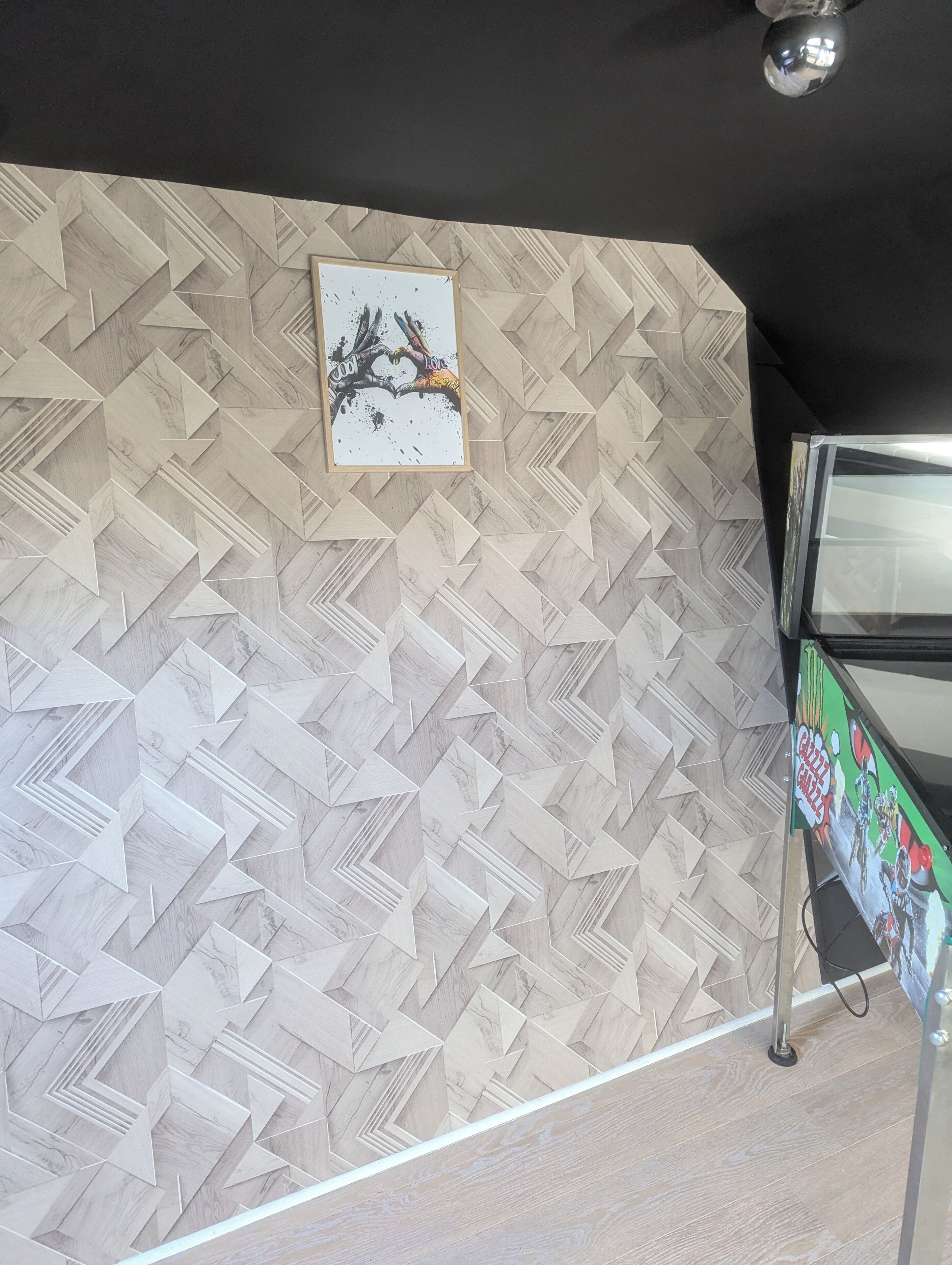 A wall with a geometric patterned design, a framed picture, and a vending machine.