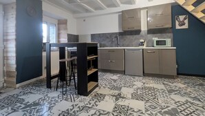 Eine kompakte Küche mit Fliesenboden, einer Bar und modernen Geräten.