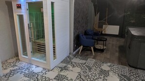 Ein Zimmer mit Sauna, gemusterten Fliesen, einem blauen Sessel und einem Holzkasten.