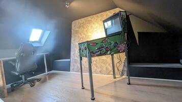 Une pièce comprenant un bureau, une chaise, une petite table ornée du logo de Monster Energy et un mur à motifs.