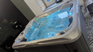 Ein Whirlpool mit integrierter Beleuchtung, einem Fenster darüber und einem gefliesten Boden.