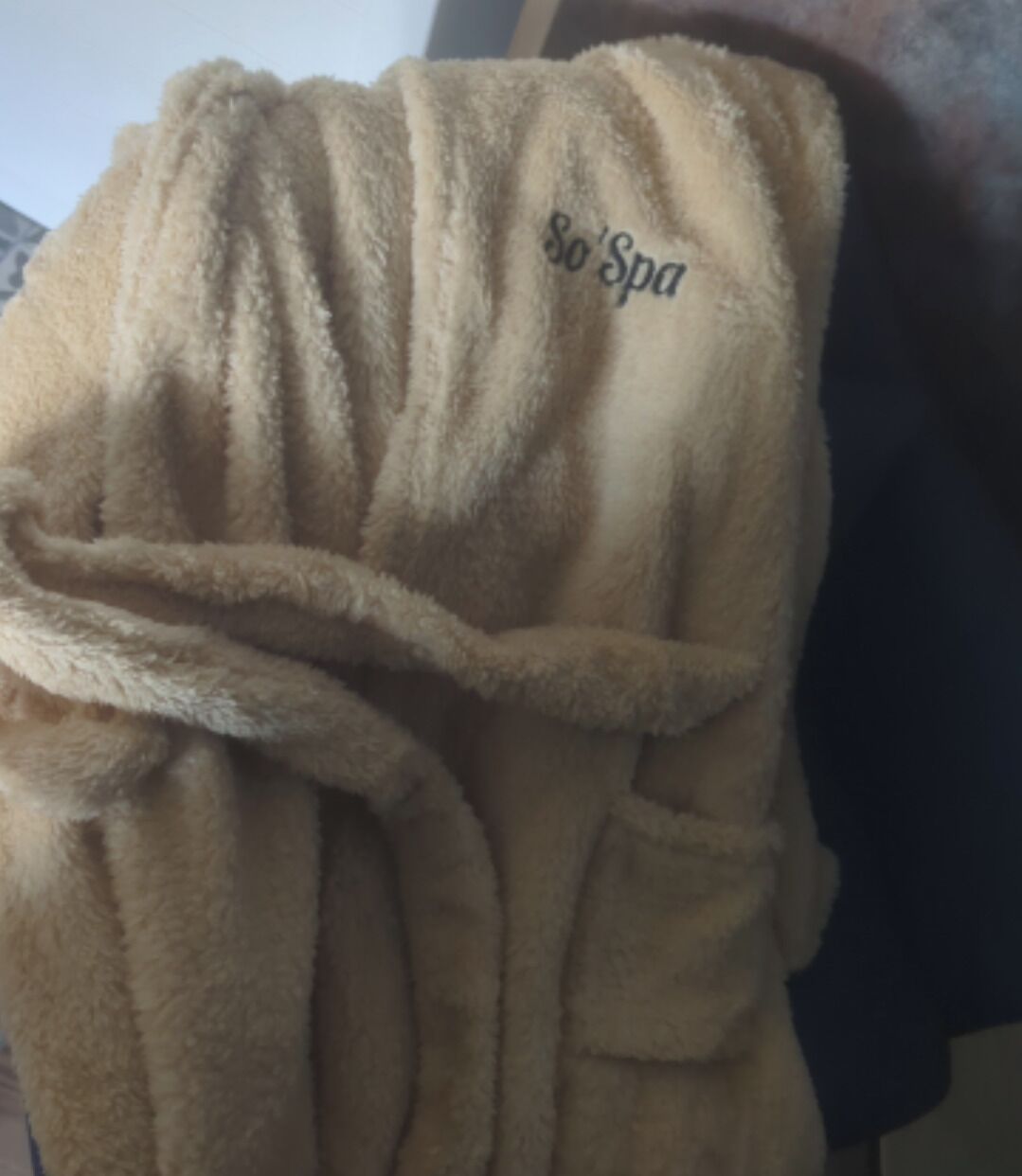 Une serviette de couleur beige avec le mot « So’Spa » brodé dessus.