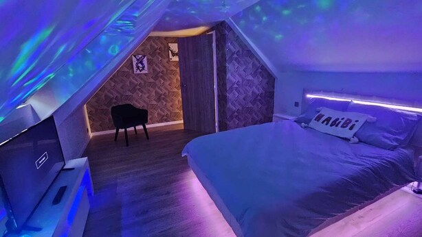 Ein Schlafzimmer mit einem Bett, einem Schreibtisch mit Computer und einem Sessel.