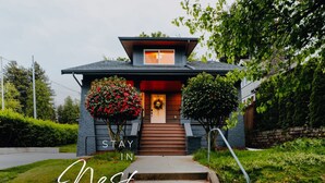 Et moderne hus med en hoveddør og trapper op til den, samt et skilt der står "STAY IN Nest".