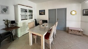 A dining area with a white cabinet, wicker chairs, a glass-top table, and a small bench. - Arcachon - T4 House Close to the Beach - 6 People (Arcachon)