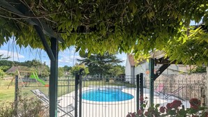 Un espacio al aire libre cercado con piscina, columpio y jardín de rosas.