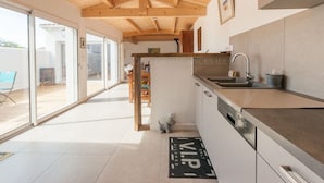 Une cuisine moderne avec des poutres en bois, un évier et une porte-fenêtre coulissante donnant sur un patio.