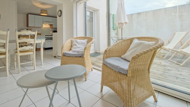 A bright, modern living area with wicker furniture, a dining table, and a view of the outside. - Apartment with terrace at Ars-en-Ré port, free Wi-Fi (Ars-en-Ré)
